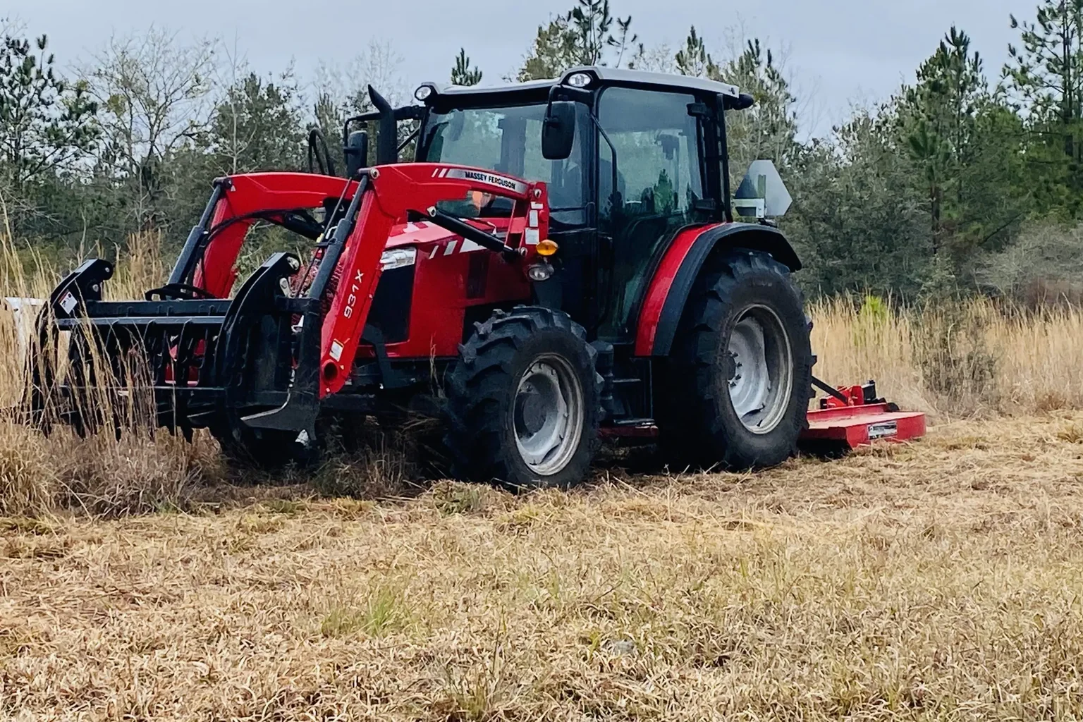 Tractor clearing dry grass on open acreage